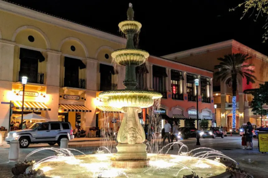 A fountain on the side of a street at night.