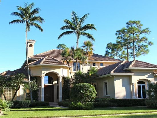 A large house with palm trees in the front yard.