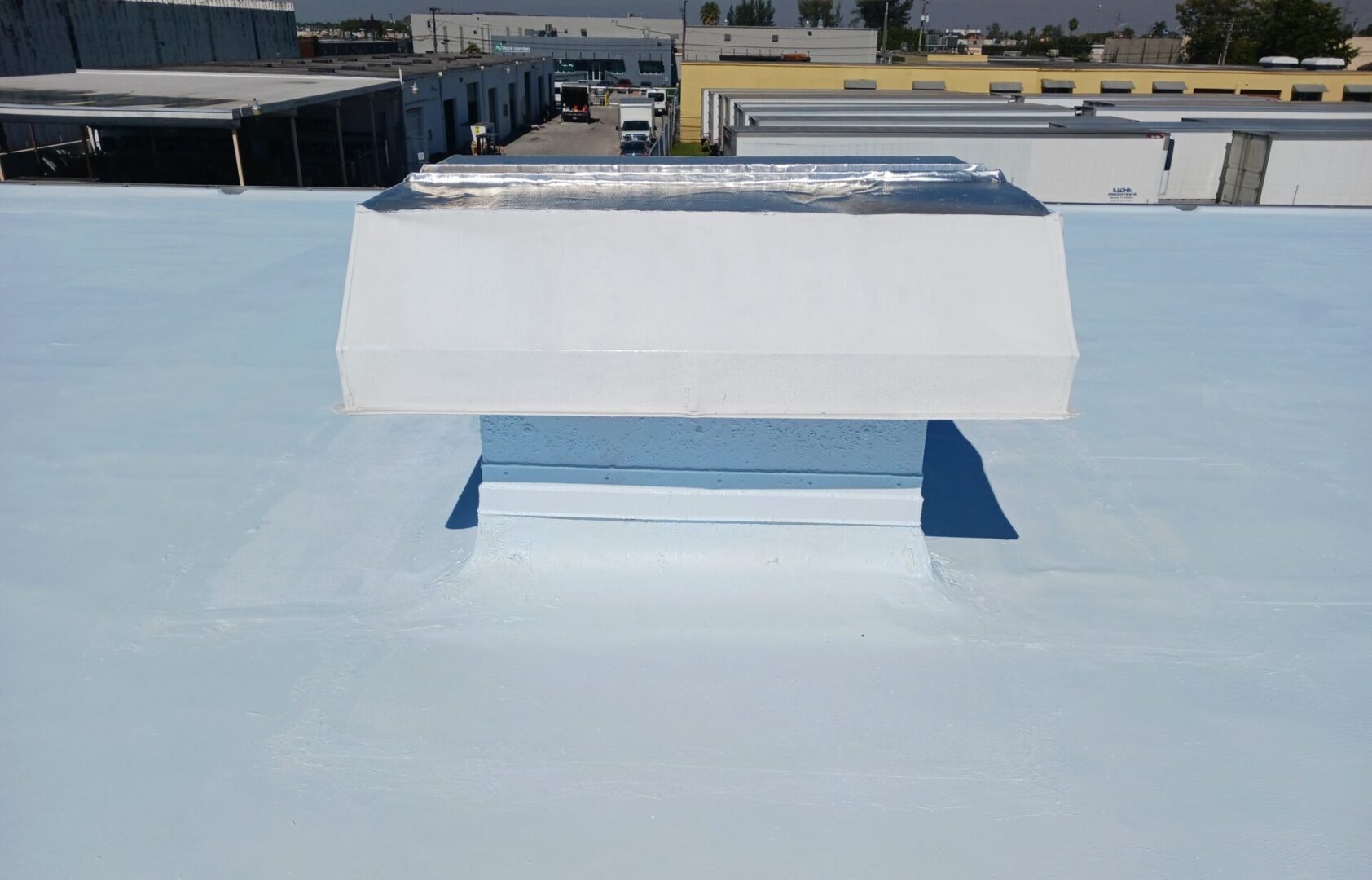 A white roof with a metal vent on it.